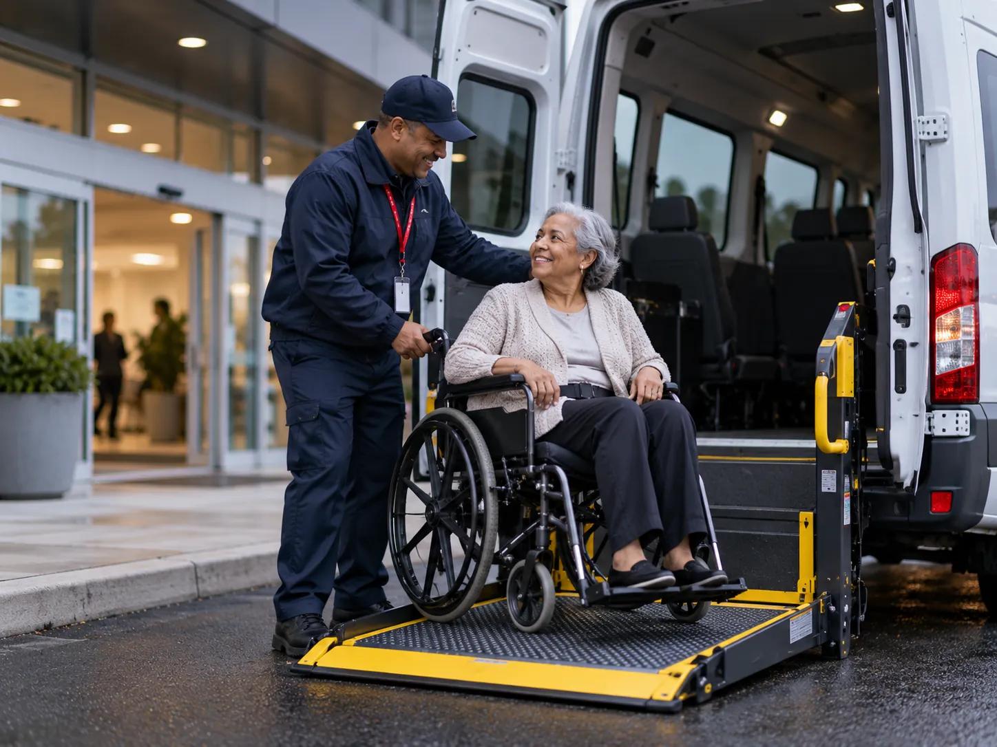 A driver helping a rider onto the van lift outside a clinic